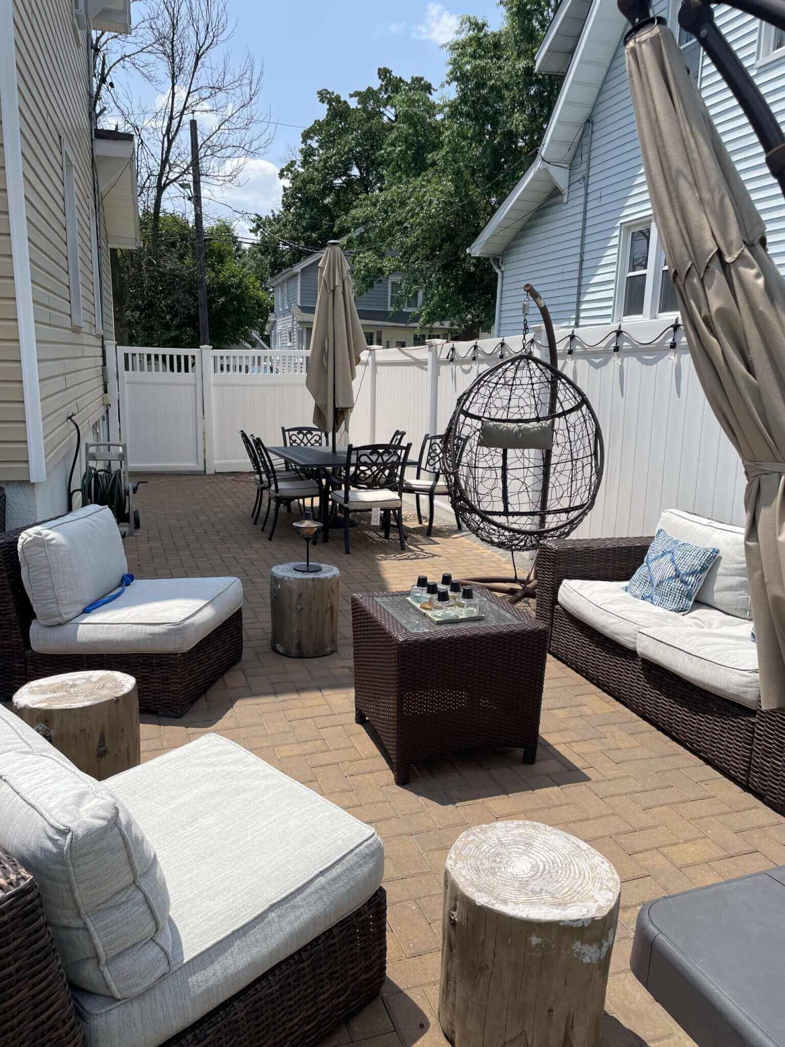 A backyard oasis featuring wicker furniture and an umbrella, beautifully landscaped by experienced professionals in Bergen County, NJ.