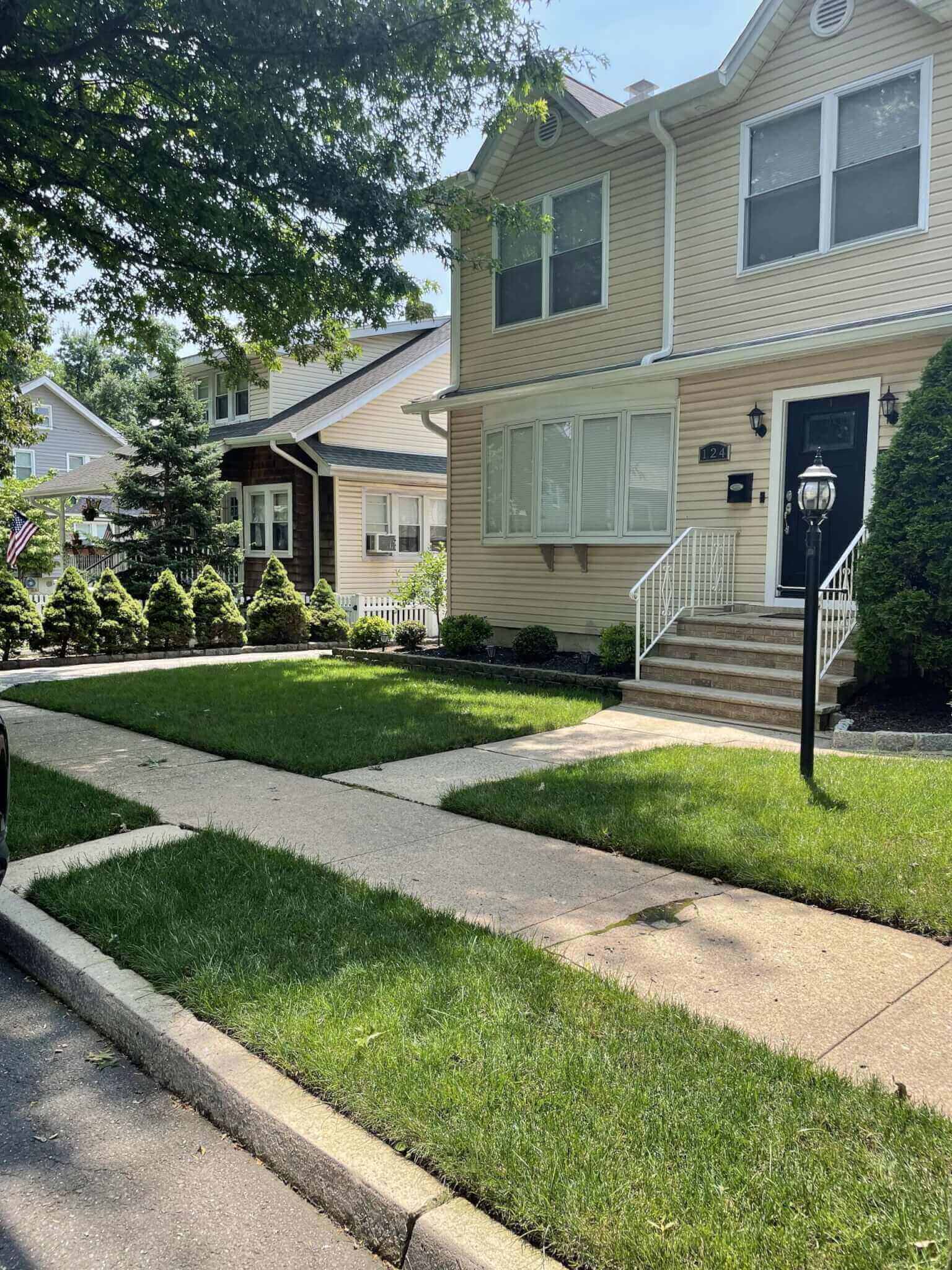 Una casa con hermosos jardines en el condado de Bergen, Nueva Jersey, con un automóvil estacionado frente.